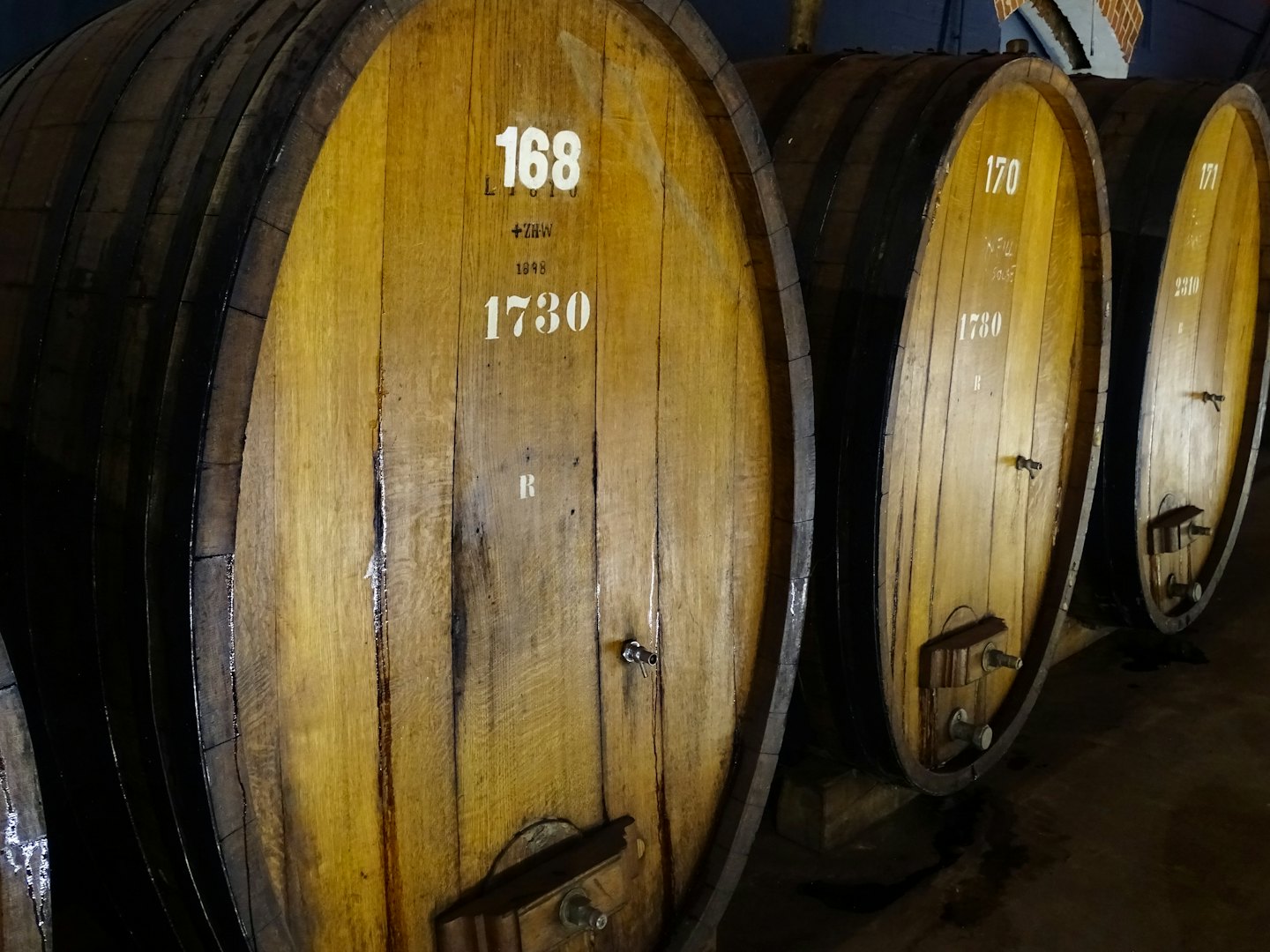Vecchie botti di vino in legno con cerchi di metallo in una cantina.