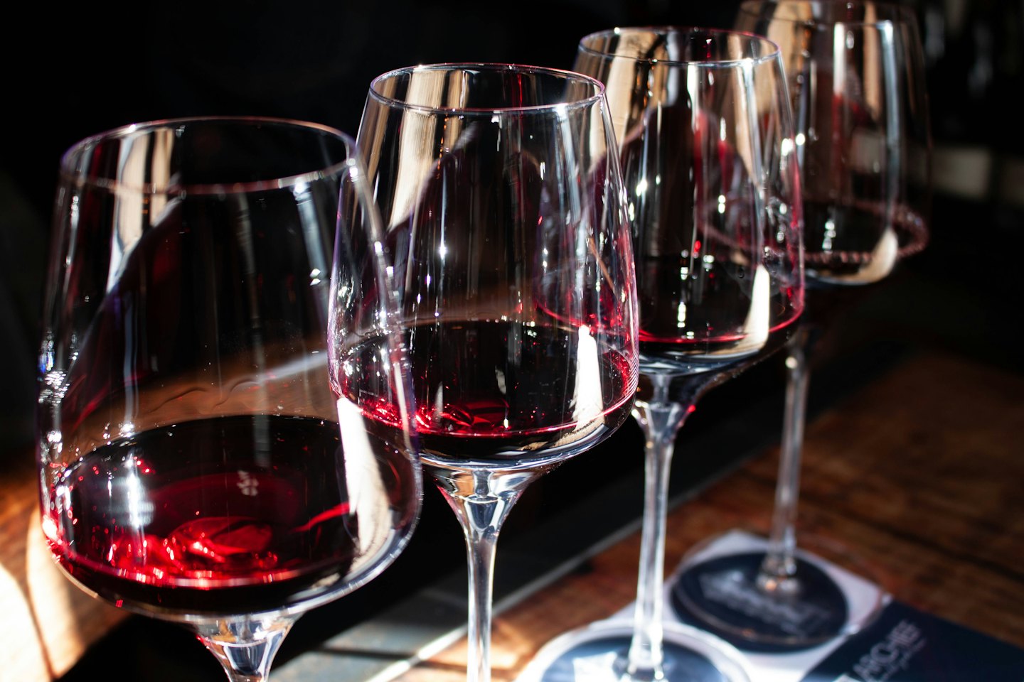Quattro bicchieri di vino rosso su un tavolo di legno.